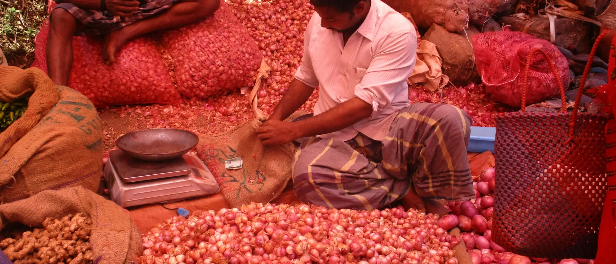 A vendor weighing small red onions at Kodaikanal market