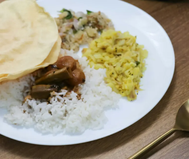 A South Indian meal of rice, papad, curry and poriyal served on a plate